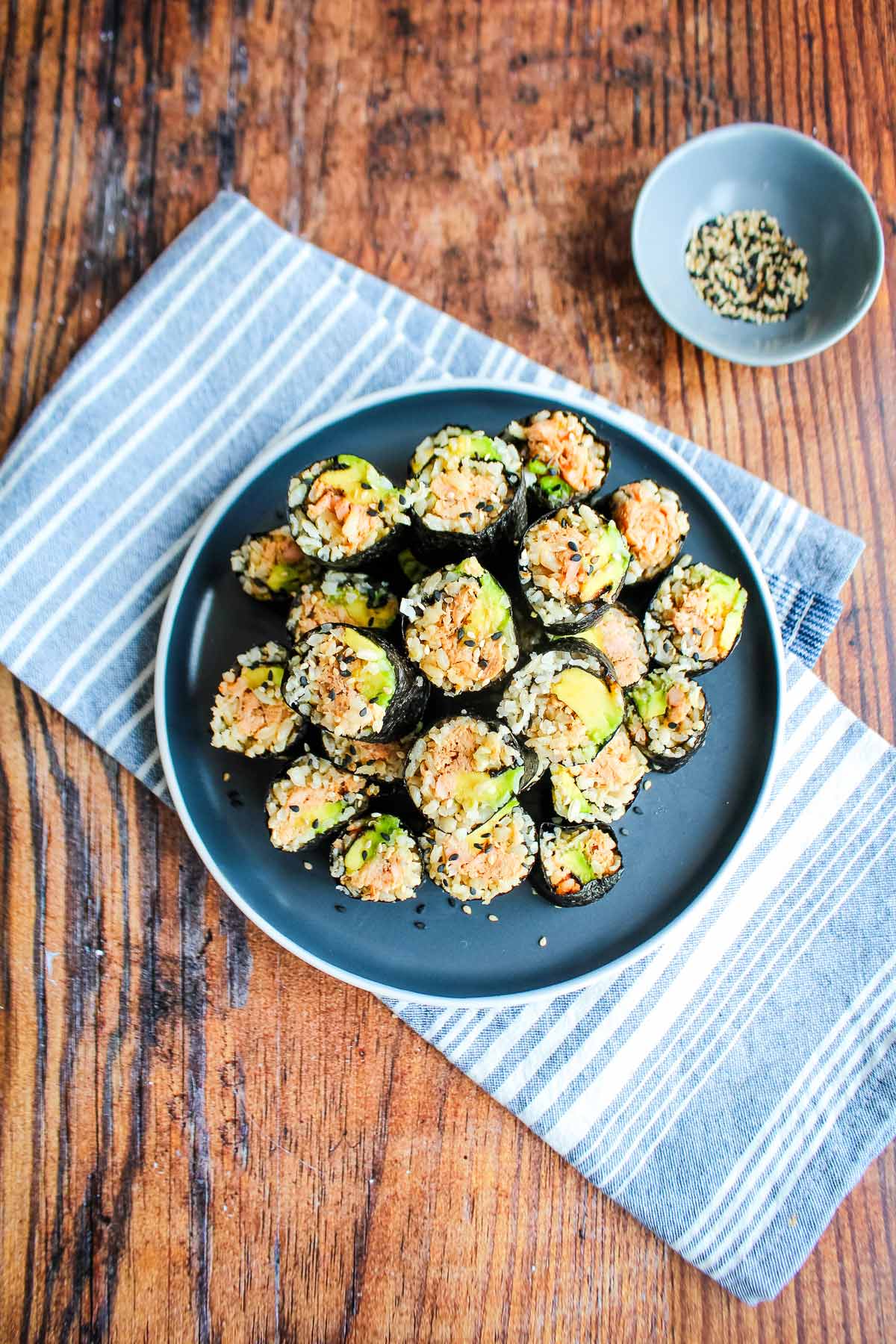 Salmon seaweed rolls cut into pieces and on a plate on top of a blue napkin.