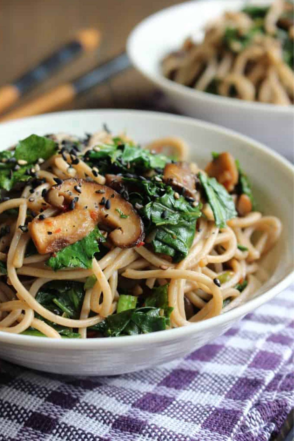 Garlic butter mushrooms with soba and leafy greens in a white bowl