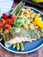 Pesto salmon with veggies on a plate.