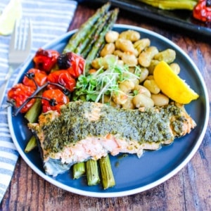 Pesto salmon with veggies on a plate.