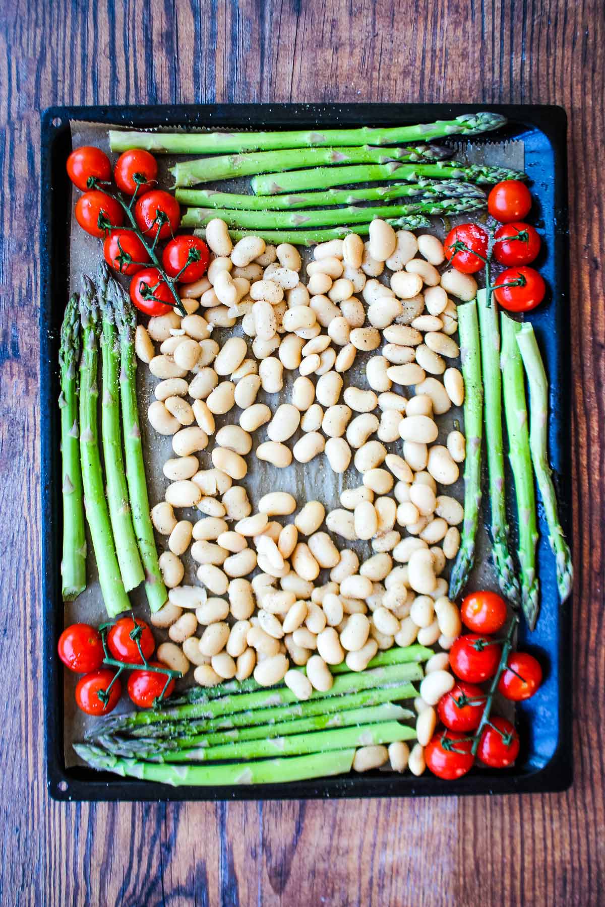 Tomatoes, beans and asparagus on a baking pan.