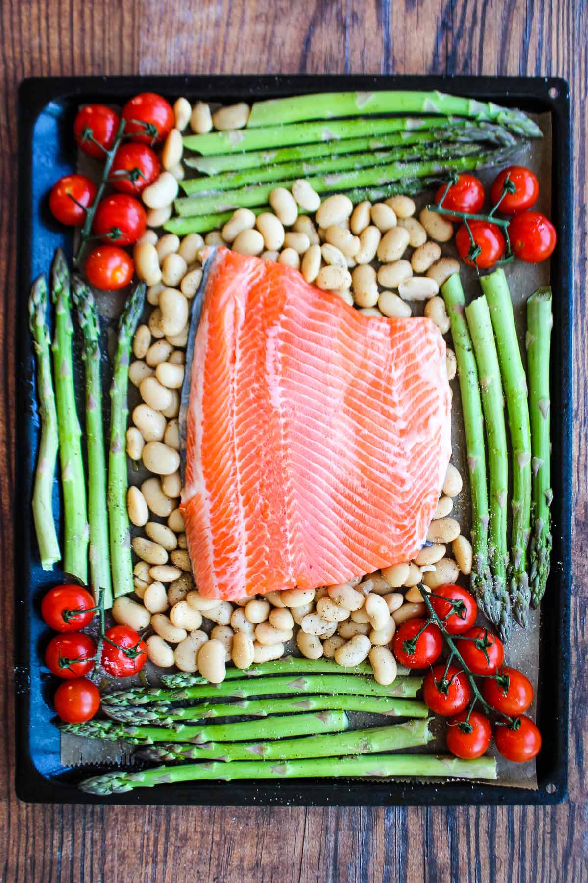 A piece of salmon placed on the sheet pan on top of the beans.