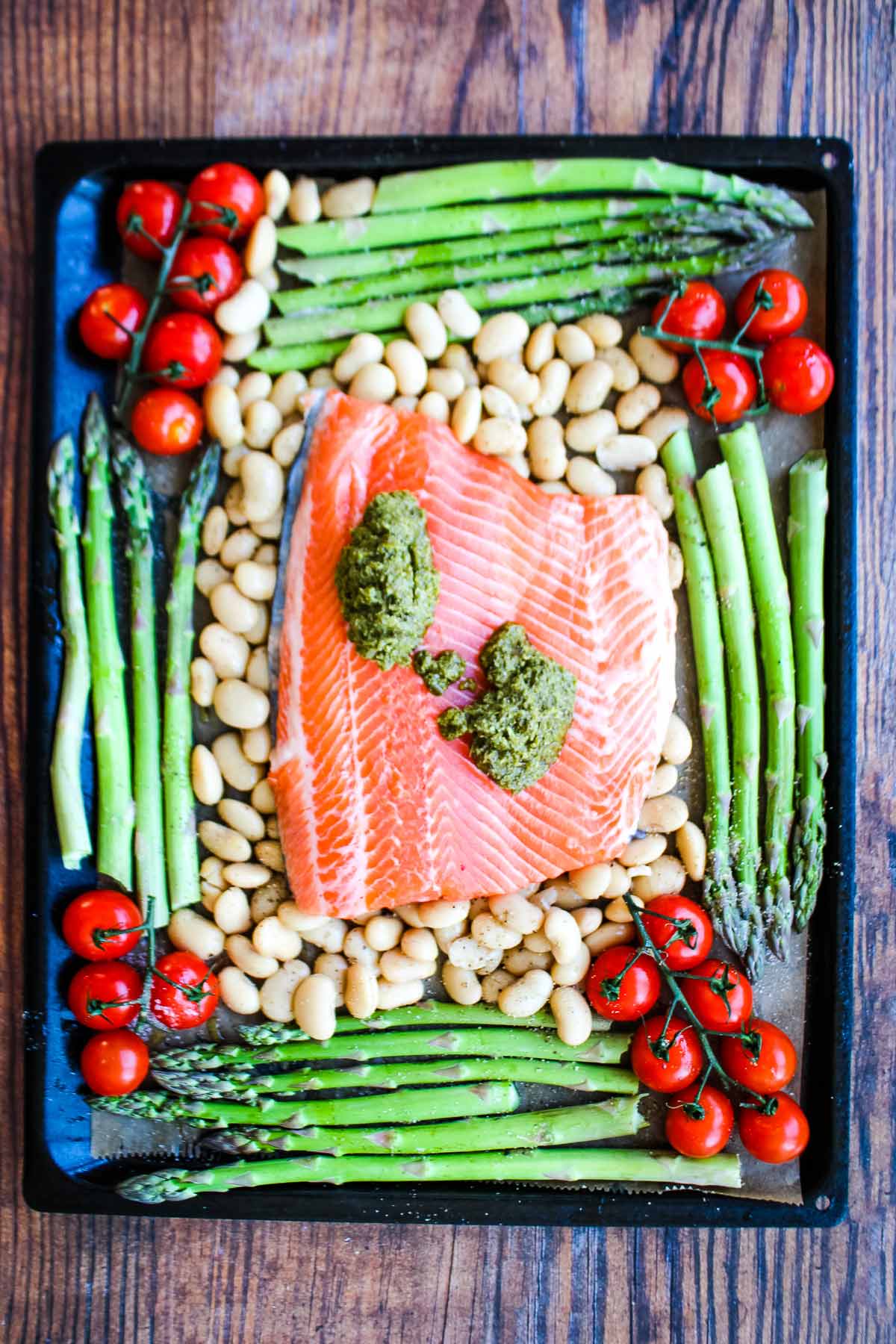 Spoonfuls of pesto added to top of salmon.