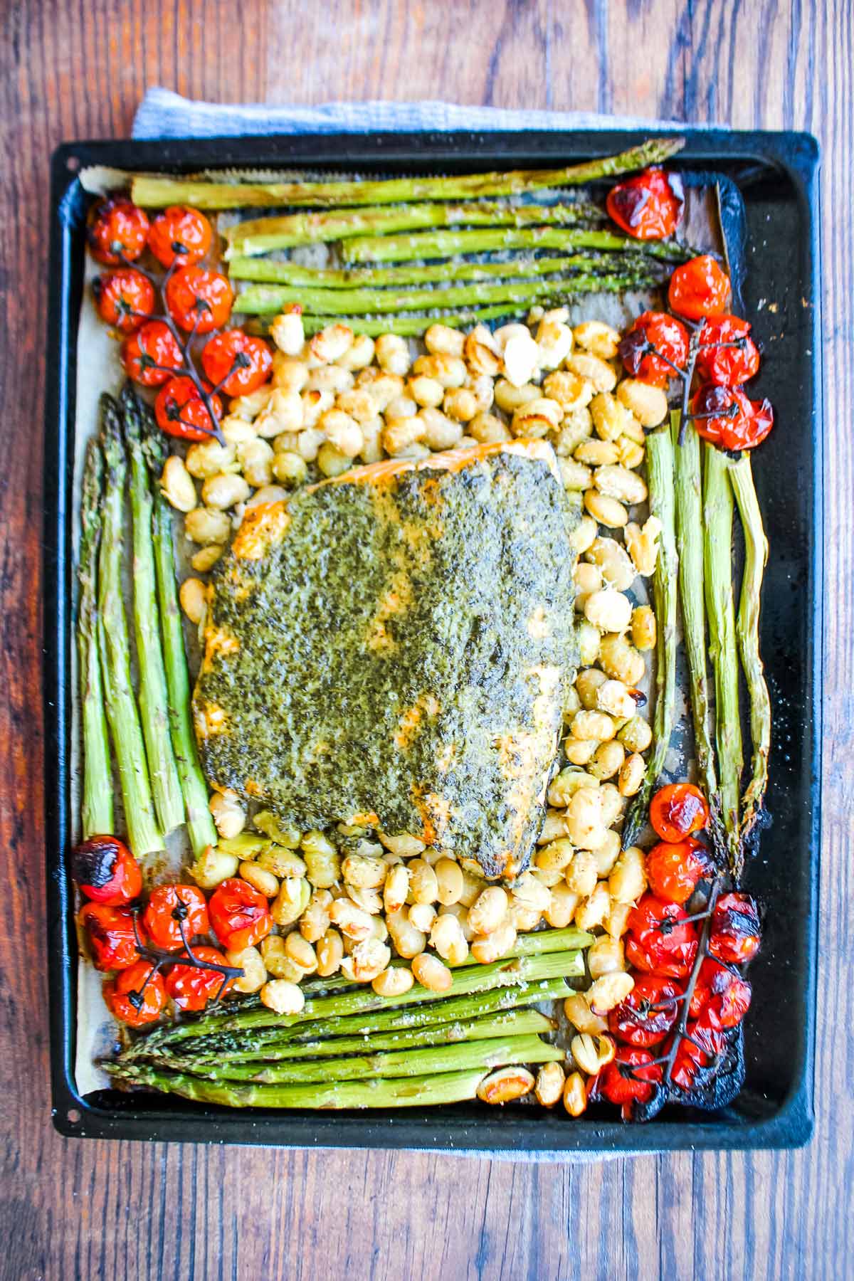 Pesto salmon and veggies on a sheet pan after baking.