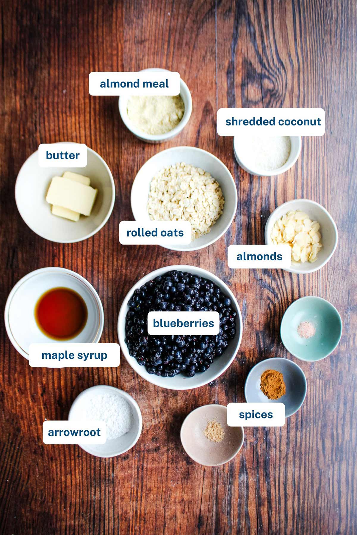 Ingredients to make gluten-free blueberry crisp on the table with text labels.