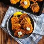 Plate of butternut squash fritters on the table with more on a pan.