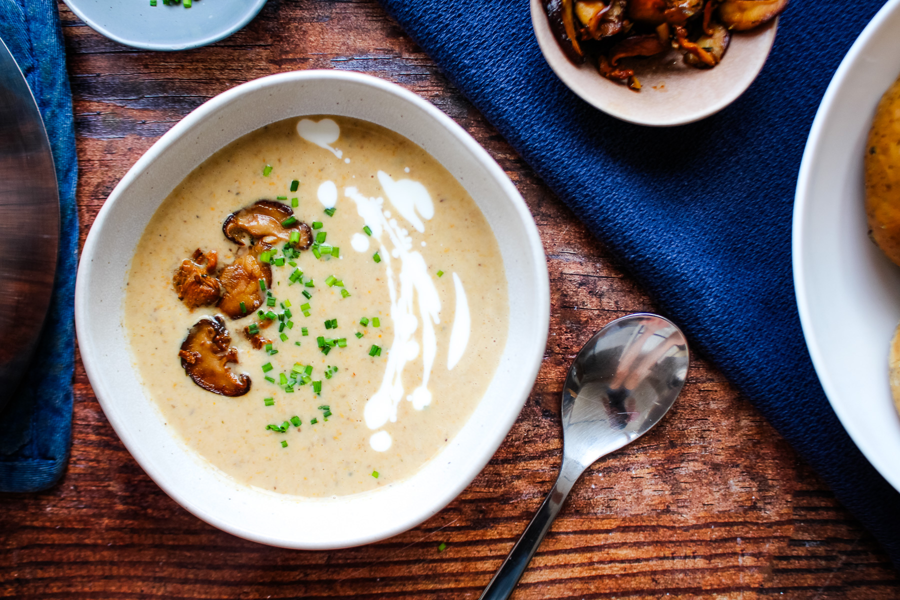 Bowl of mushroom bisque soup on the table with a spoon to the right side of the bowl.