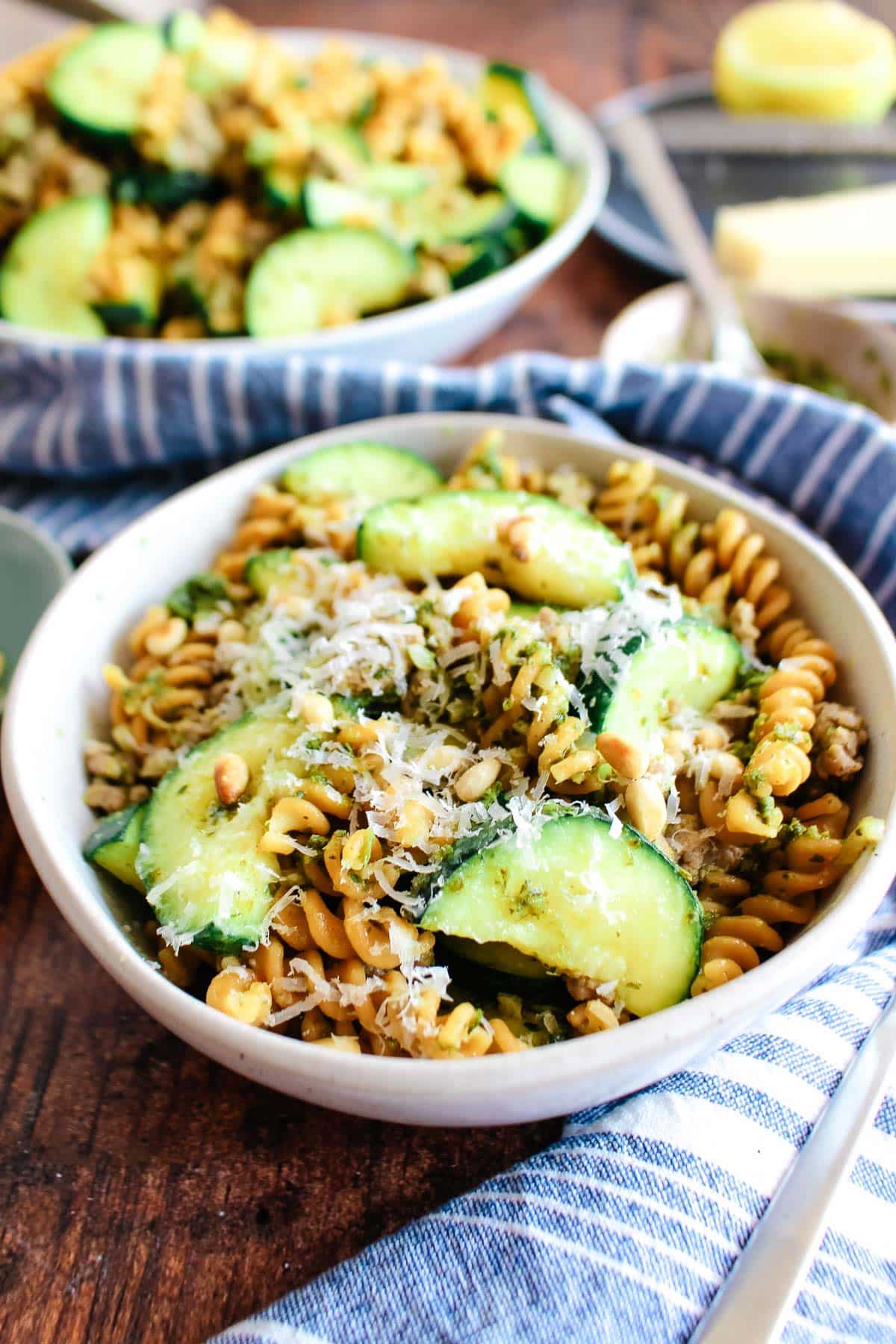 A closeup of a bowl of zucchini pesto pasta on the table.