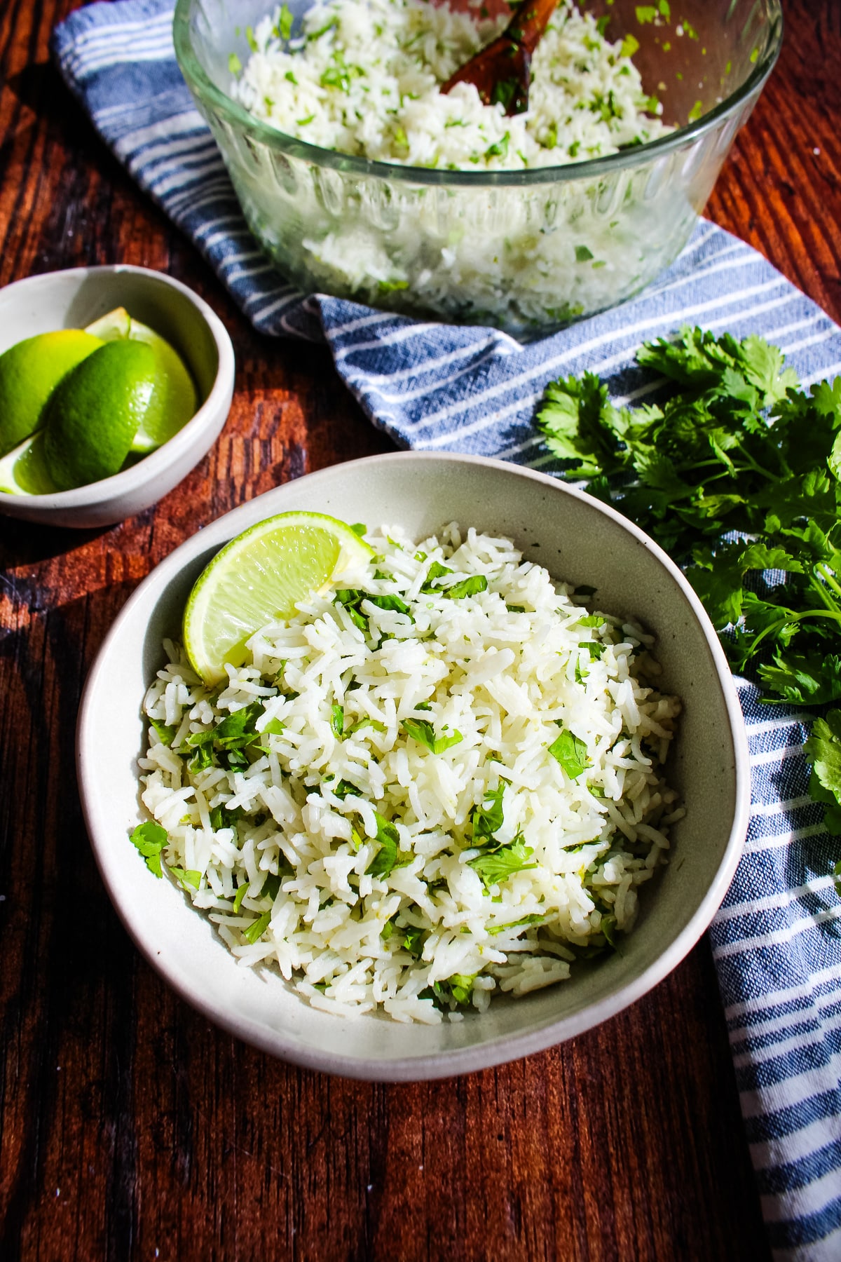 Bowl of white rice mixed with cilantro and lime juice, with a lime wedge as a garnish.