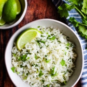 Bowl of white rice mixed with flecks of cilantro, topped with a lime wedge.