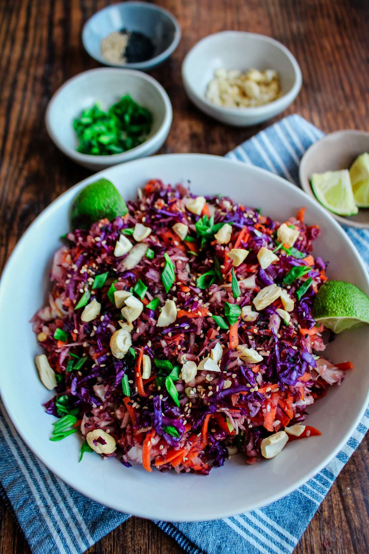 Asian cabbage crunch salad in a bowl on a table with a blue tea towel and small bowls of ingedients.