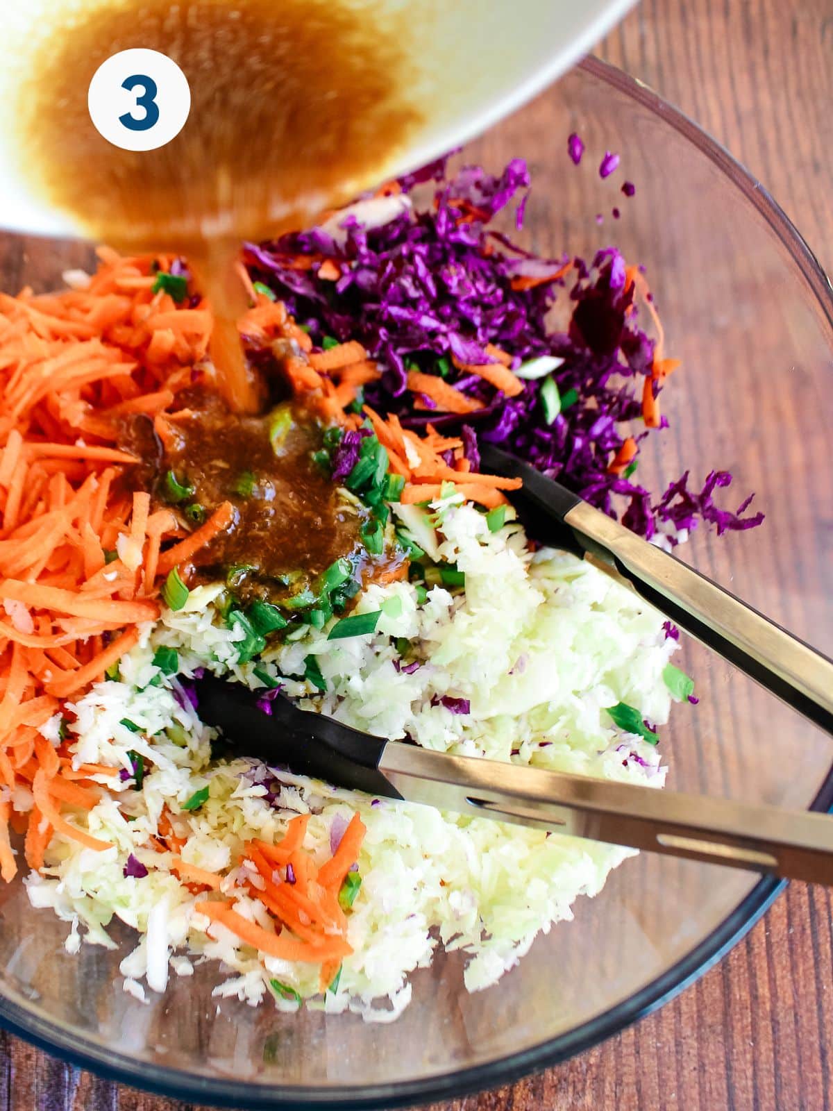 Adding the cabbage salad dressing to the vegetables.