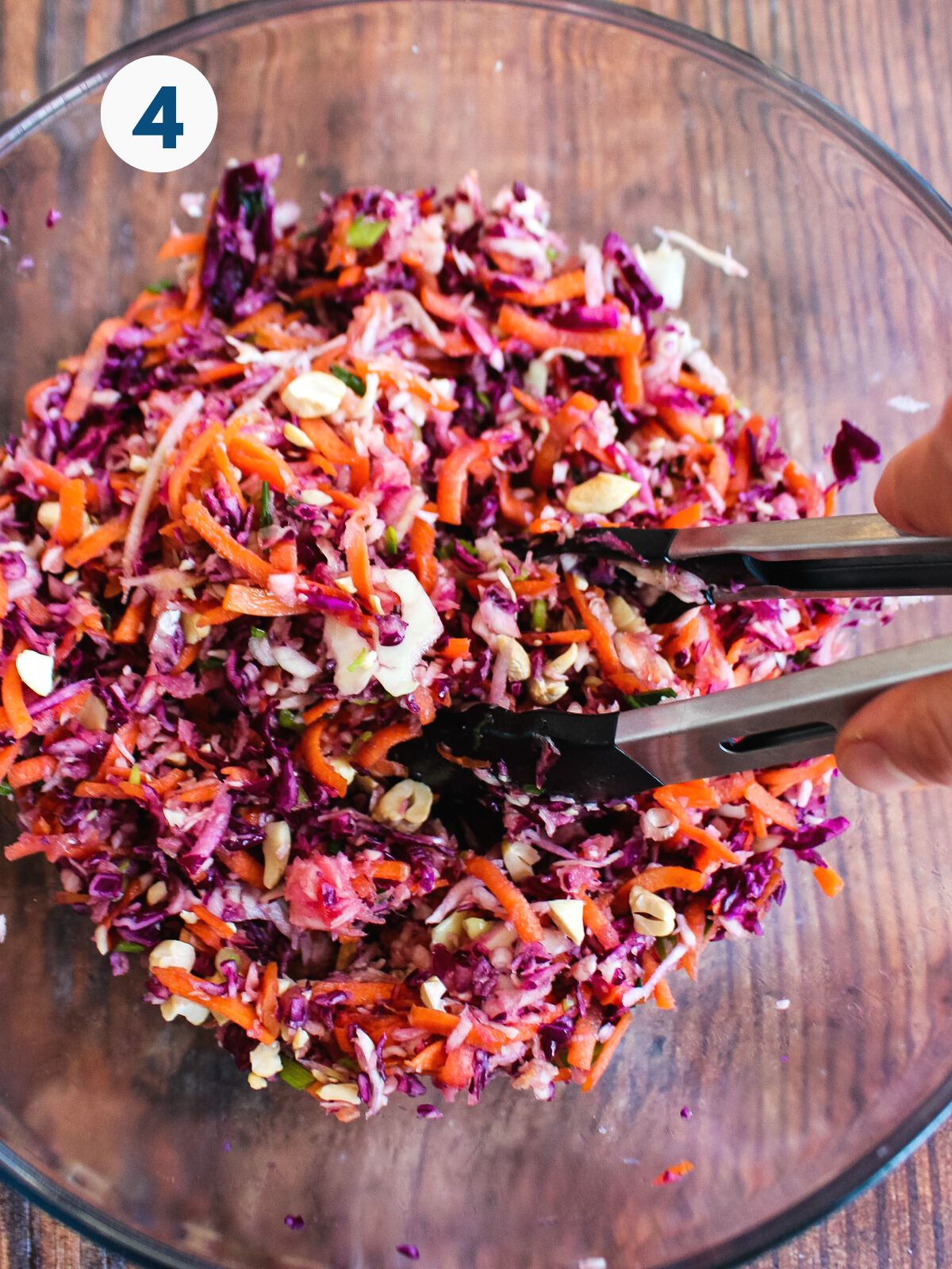 Everything all mixed together in a glass bowl with tongs.