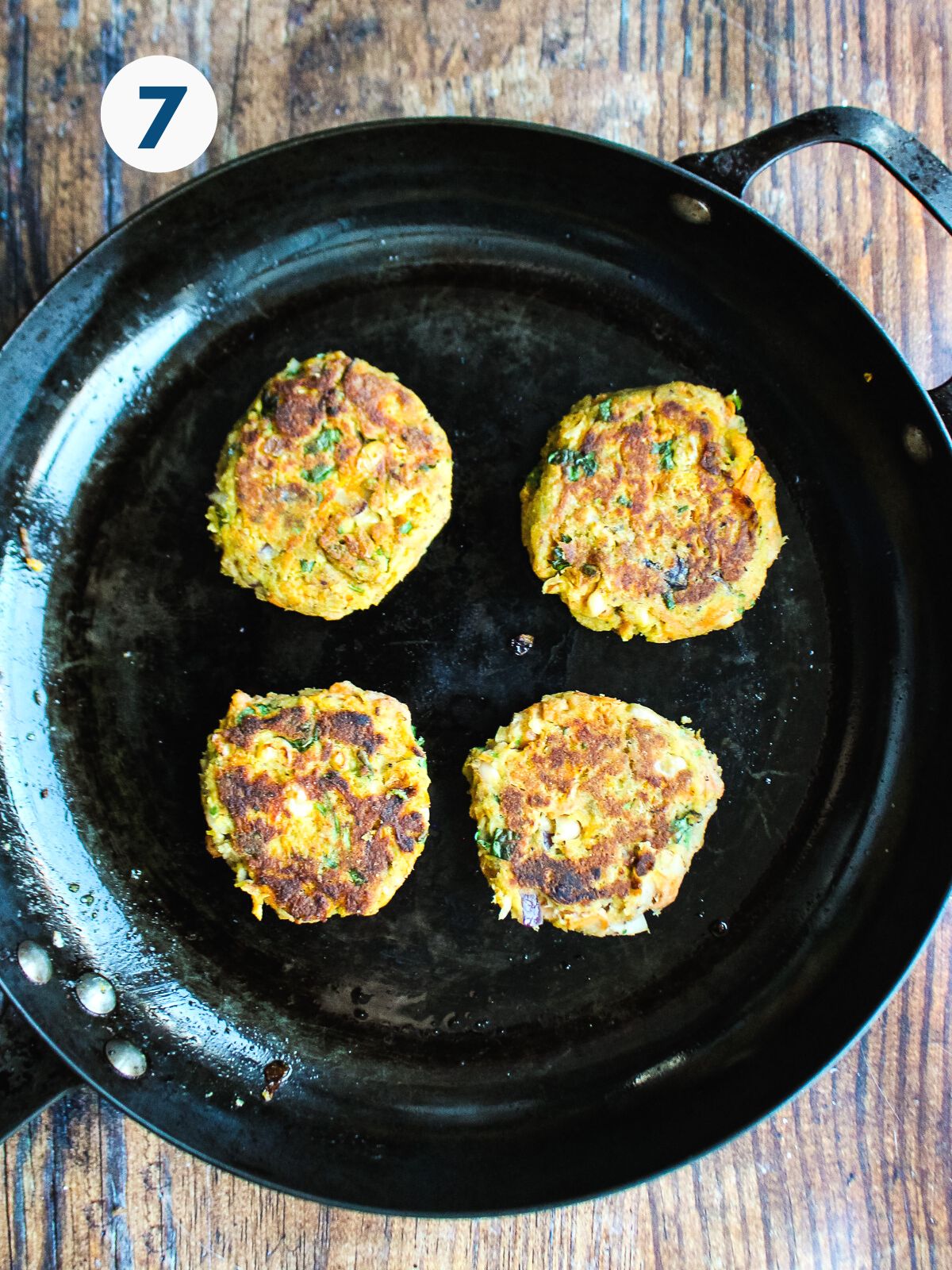 Sardine cakes cooking in a pan.