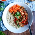 A plate of peanut butter chicken served up on the table with brown rice.