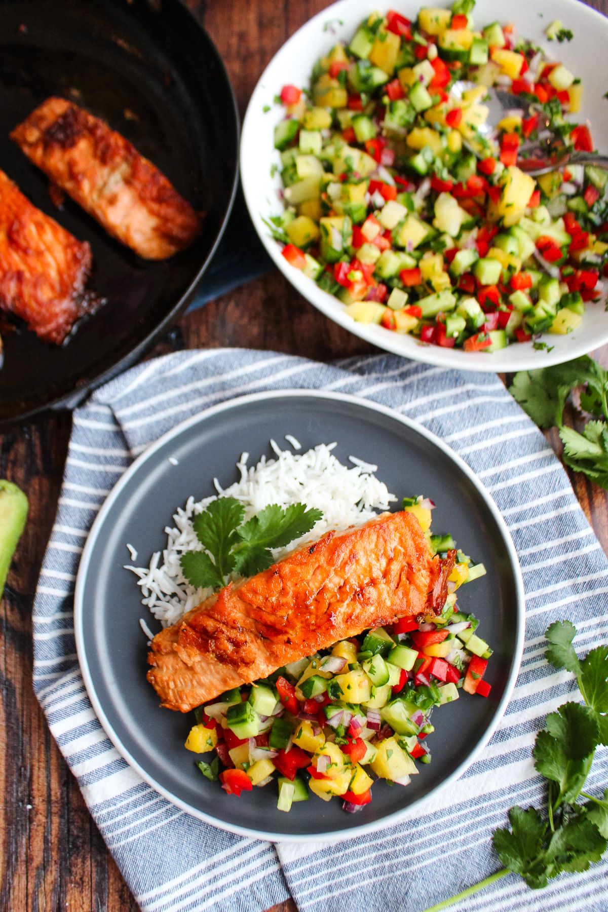 Pineapple salmon on a plate on the table with bowl of pineapple salsa.