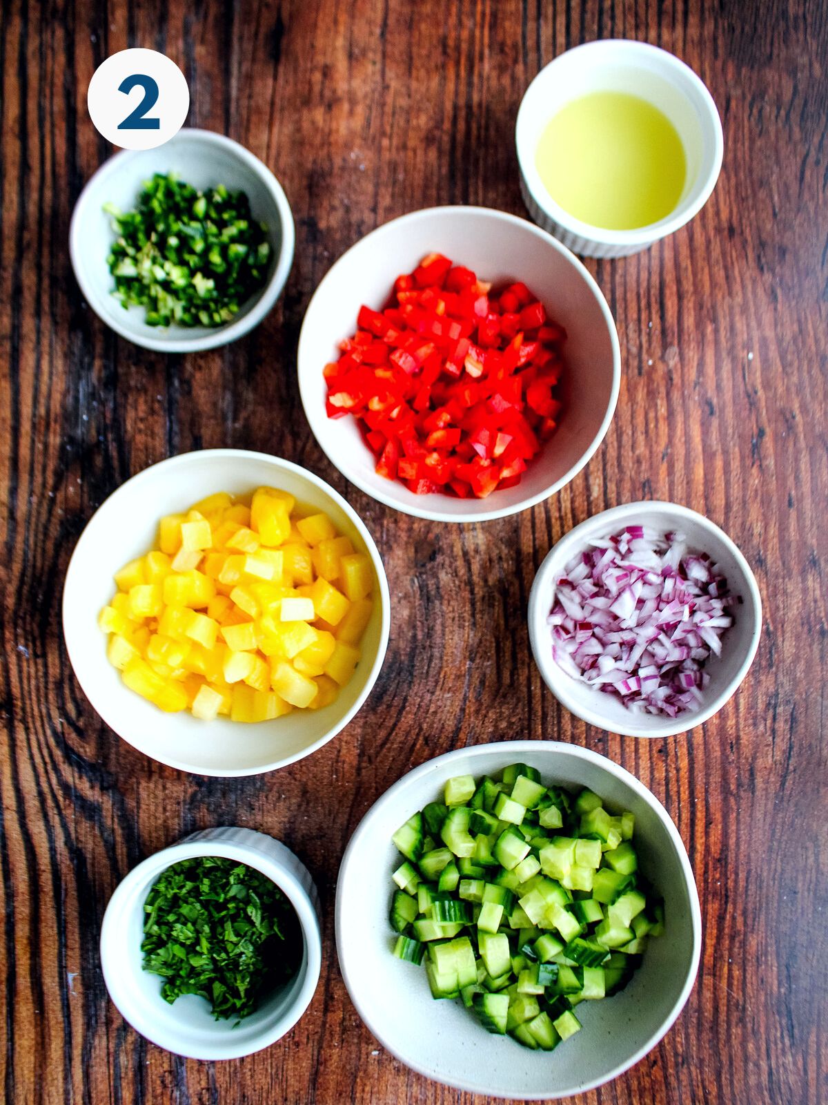 Vegetables for the pineapple salsa diced in bowls on the table.