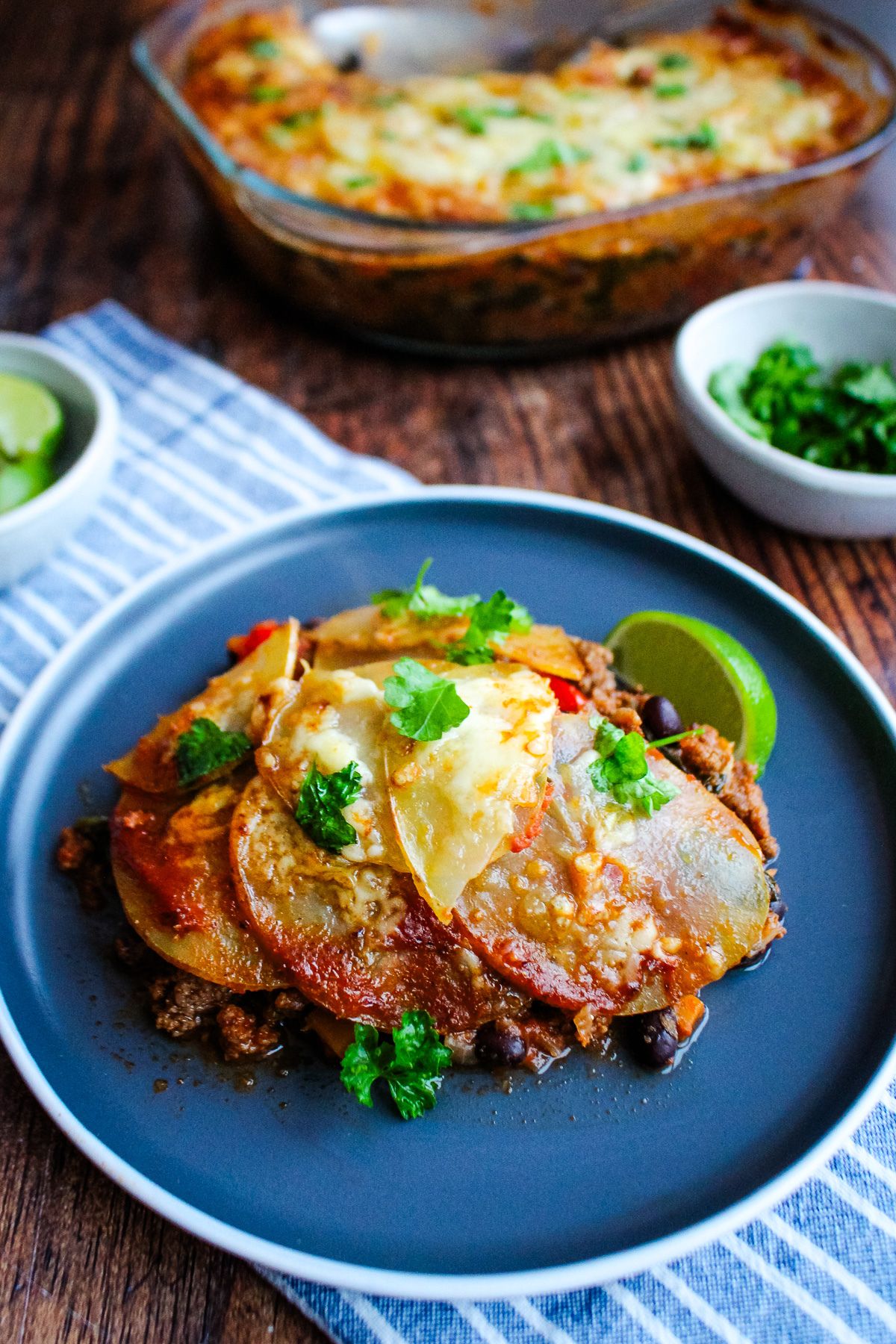 Taco potato bake served up on a plate with the casserole dish in the background.