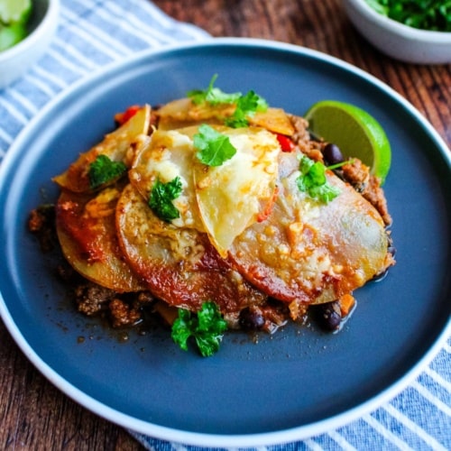 Taco potato casserole served up on a plate with a lime wedge.