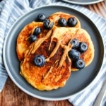 A plate of cottage cheese oatmeal pancakes with almond butter and blueberries.