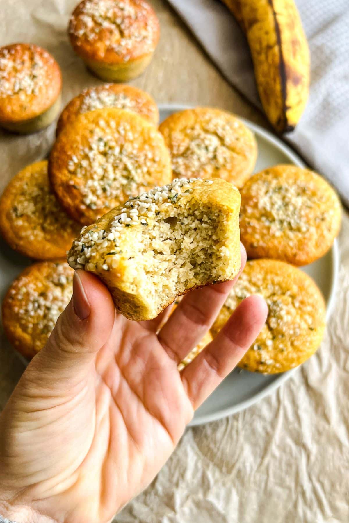 A hand holding up a almond flour banana muffin with a bite missing.