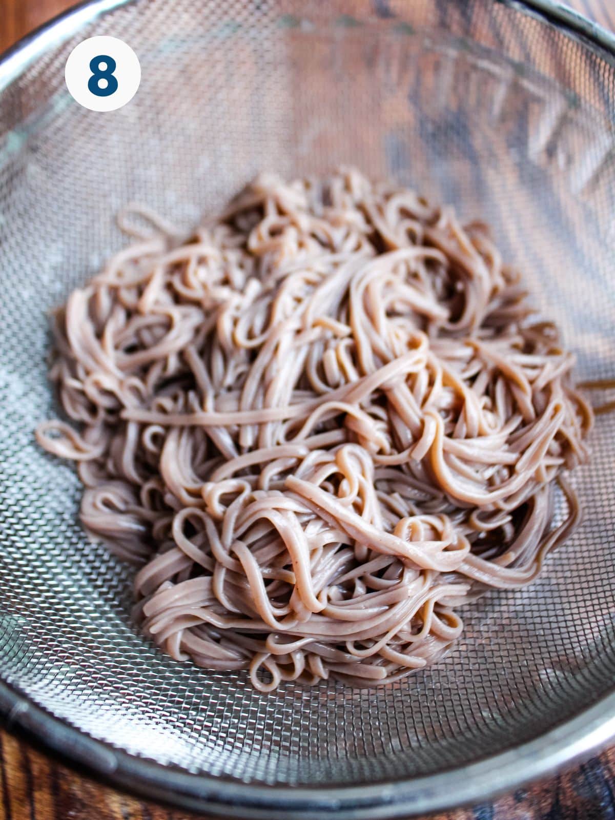 Soba noodles draining in a strainer.