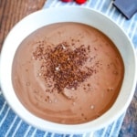 A bowl of chocolate tofu mousse on a blue napkin sprinkled with cocoa powder.