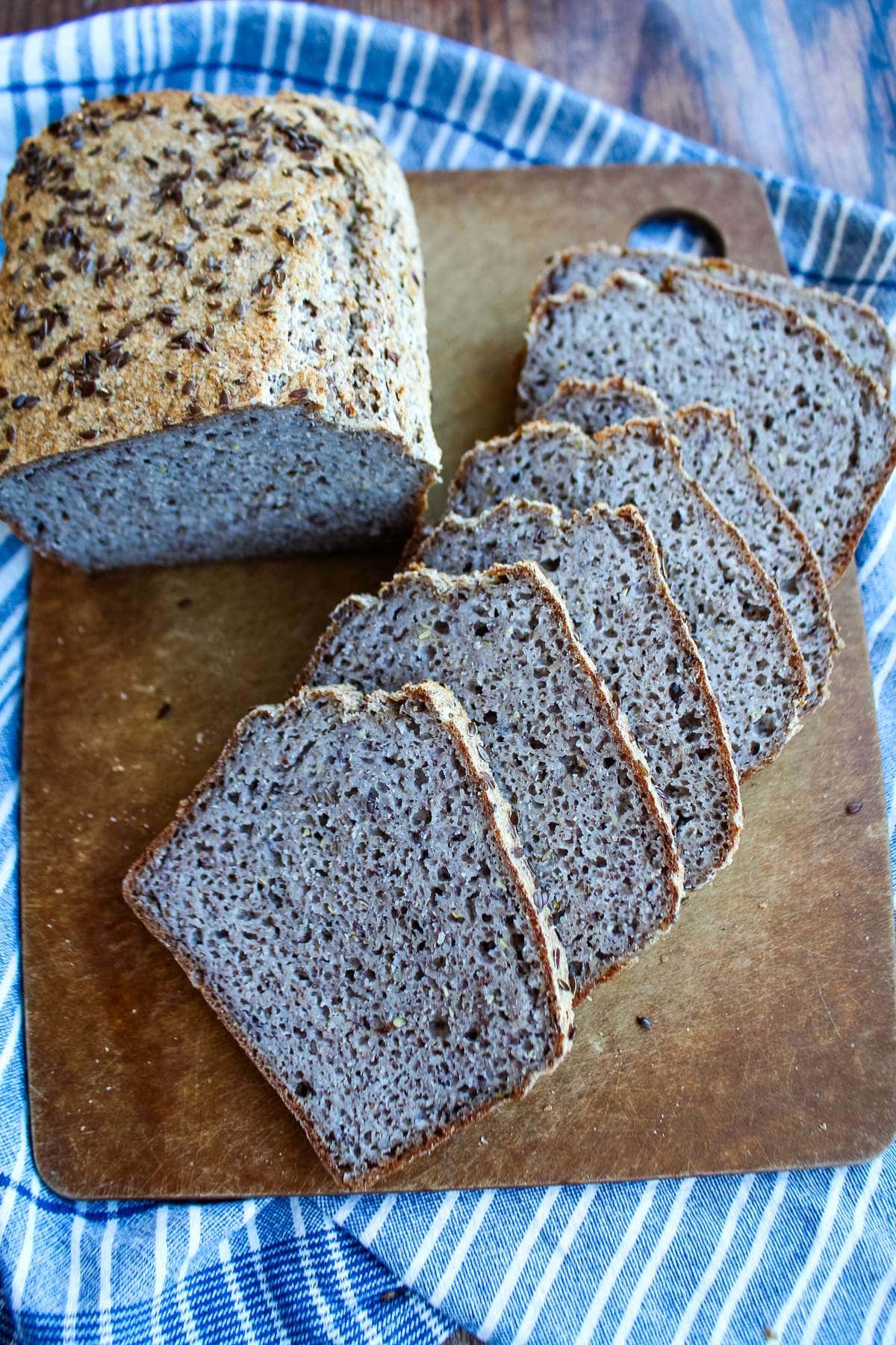 Buckwheat bread on a cutting board cut into slices with a partial loaf uncut to the side.