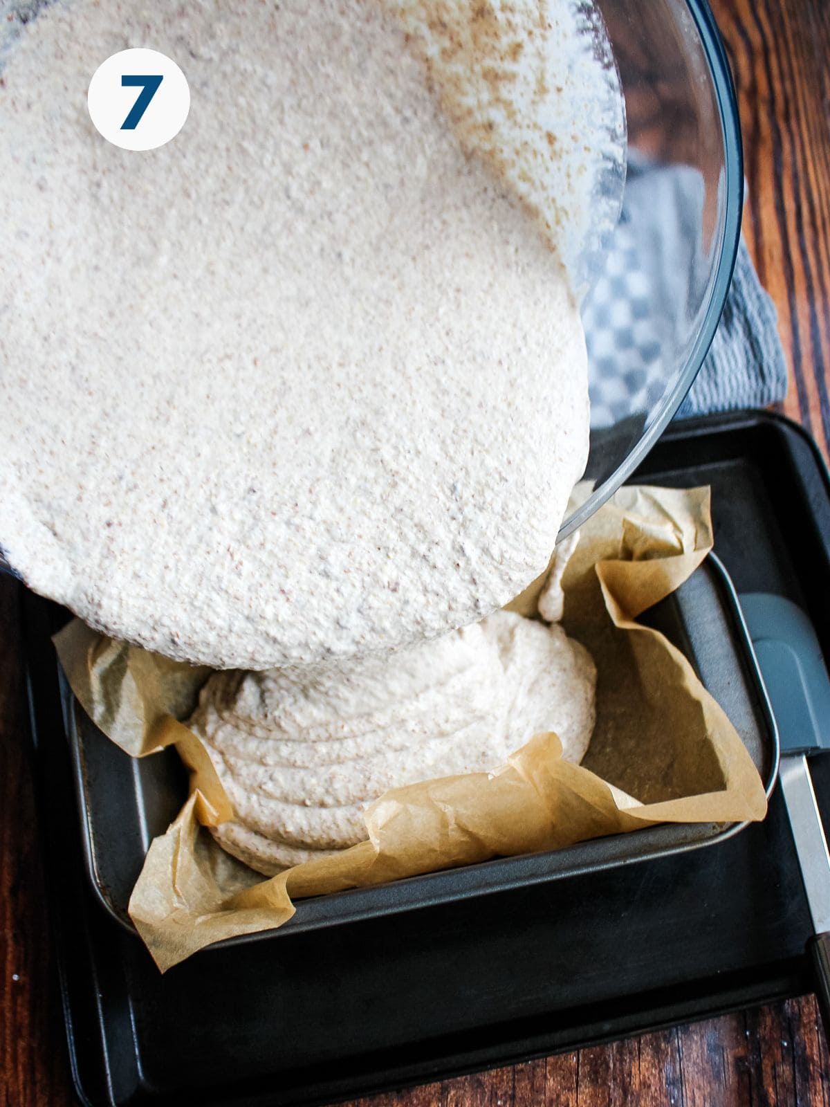 Pouring the buckwheat bread batter into a parchment lined loaf pan.