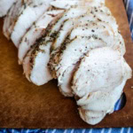 Sliced slow cooker turkey breast on a wooden cutting board.