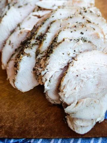 Sliced slow cooker turkey breast on a wooden cutting board.