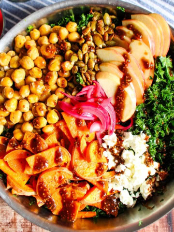 A bowl of harvest salad with the different toppings in groups on top of the kale.
