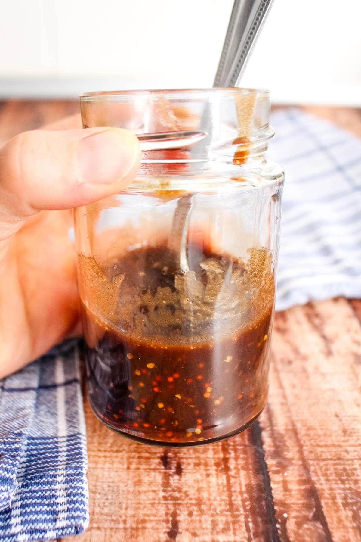 Whole grain mustard balsamic dressing in a small jar with a spoon.