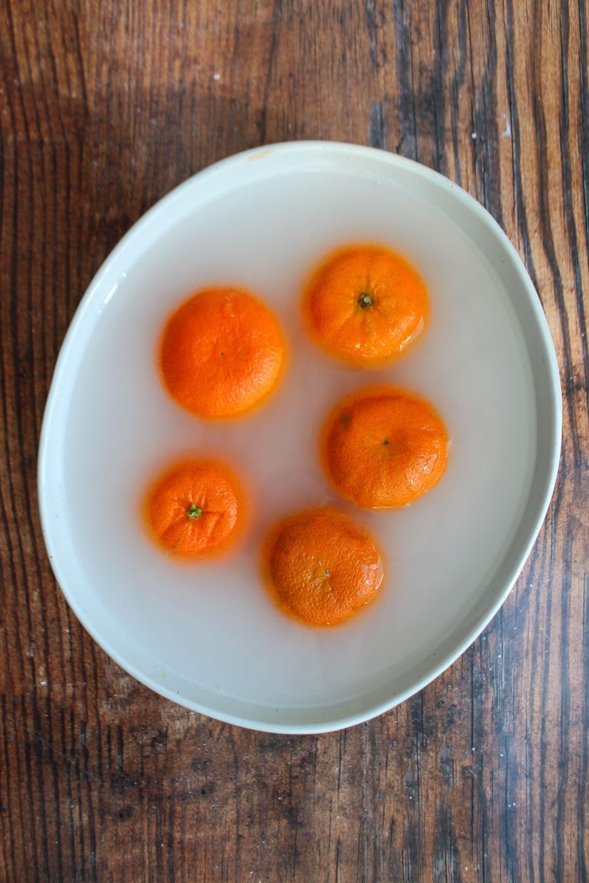 Clementines soaking in baking soda water bath.