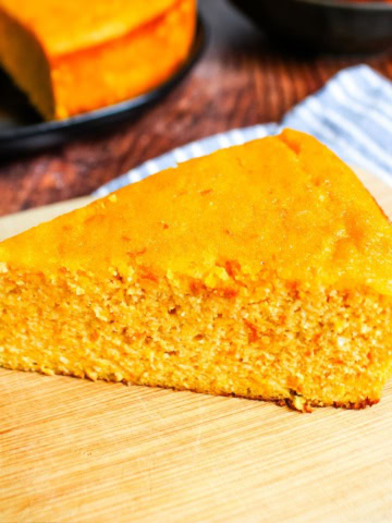 A slice of clementine cake in front of the whole cake.