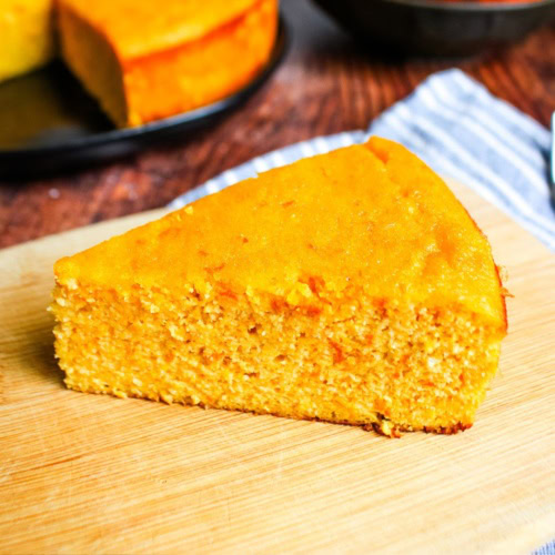 A slice of clementine cake in front of the whole cake.